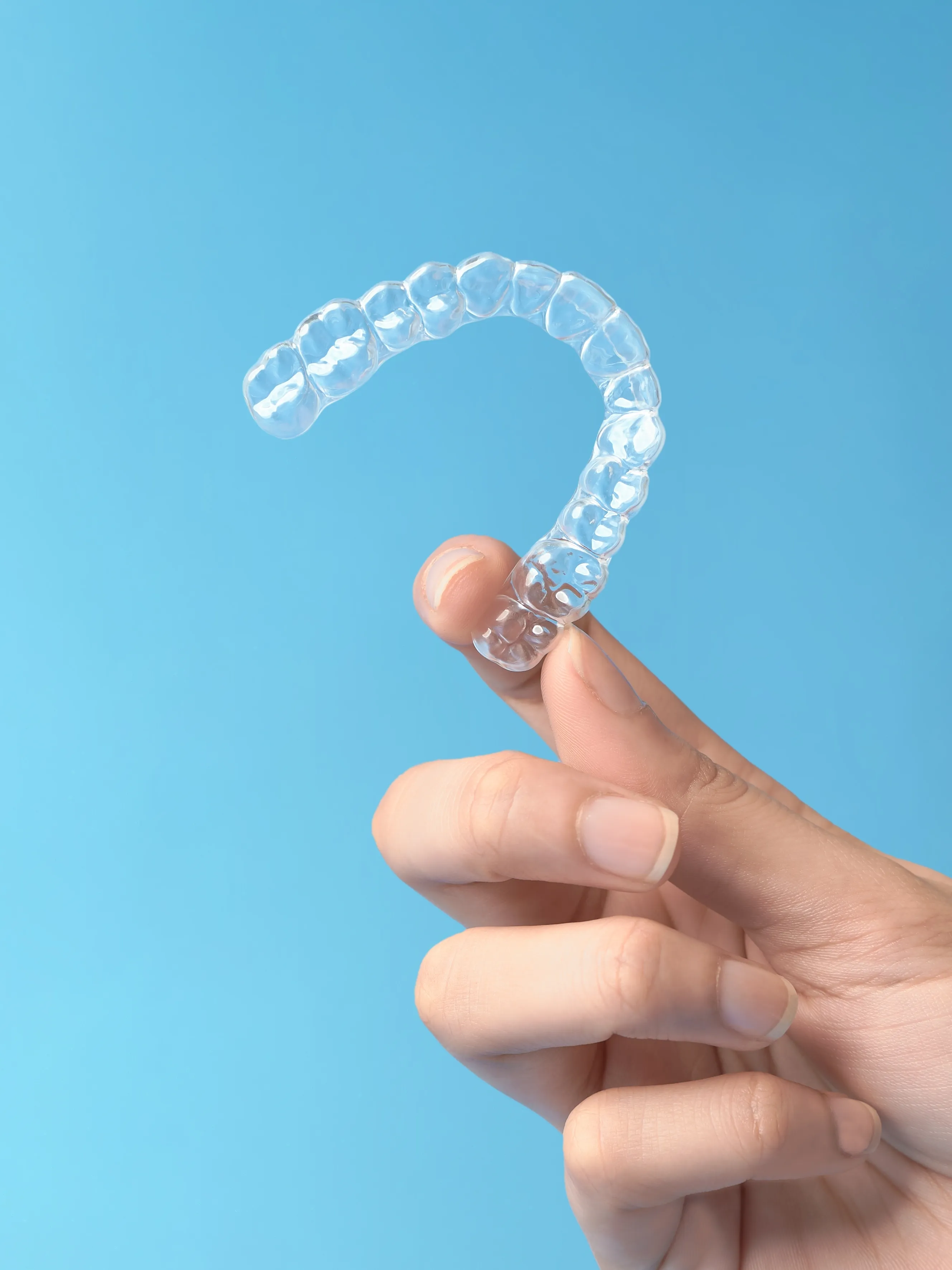 Hand holding a clear Invisalign aligner